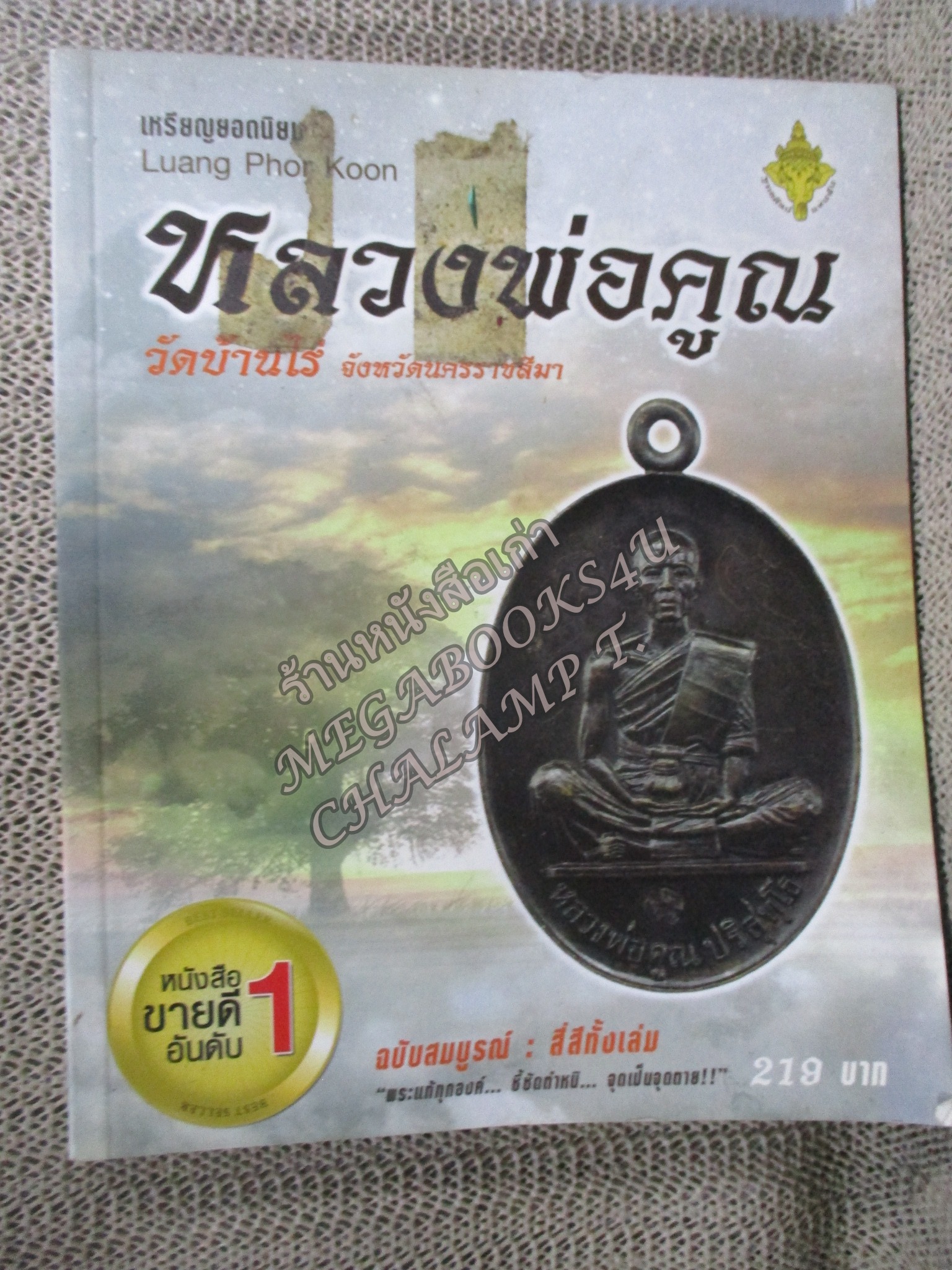 หนังสือ เหรียญยอดนิยม หลวงพ่อคูณ วัดบ้านไร่ ฉบับสมบูรณ์ / ตำหนิมีรอยเทปที่บนปกหน้า / มุมด้านล่างหนังสือเยินหน่อย